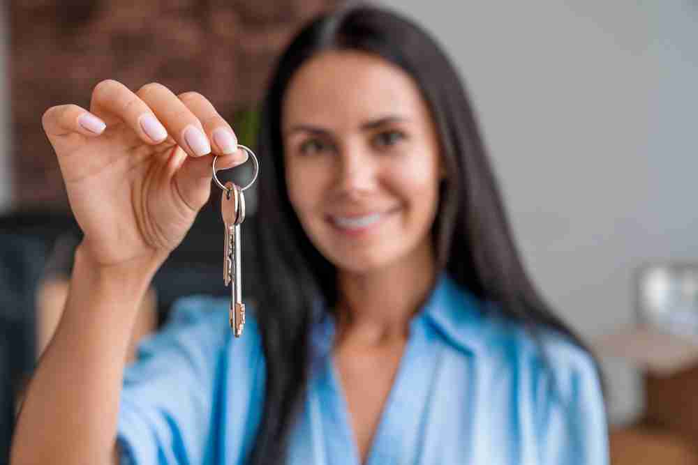 Smiling,Woman,With,Keys,From,Her,New,House,In,Living,room