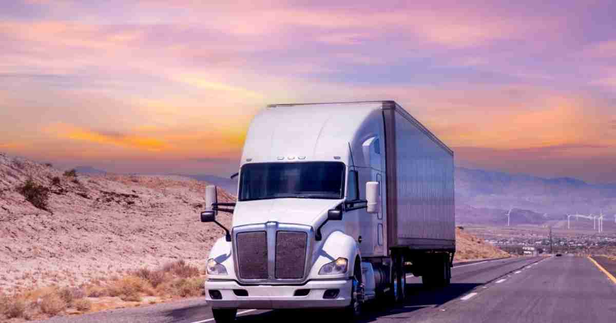 Specialized moving truck driving down the highway at sunset. 