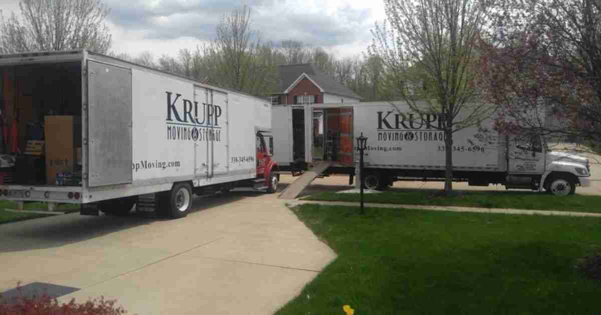 Two Krupp Moving & Storage branded moving trucks parked in front of a home with ramps down while Xenia movers complete a residential move