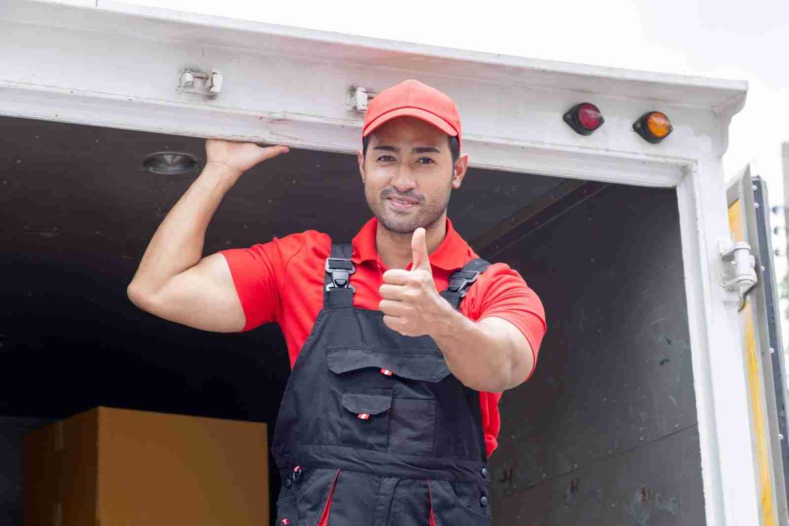 Mover standing in the back of a moving truck giving a thumbs up