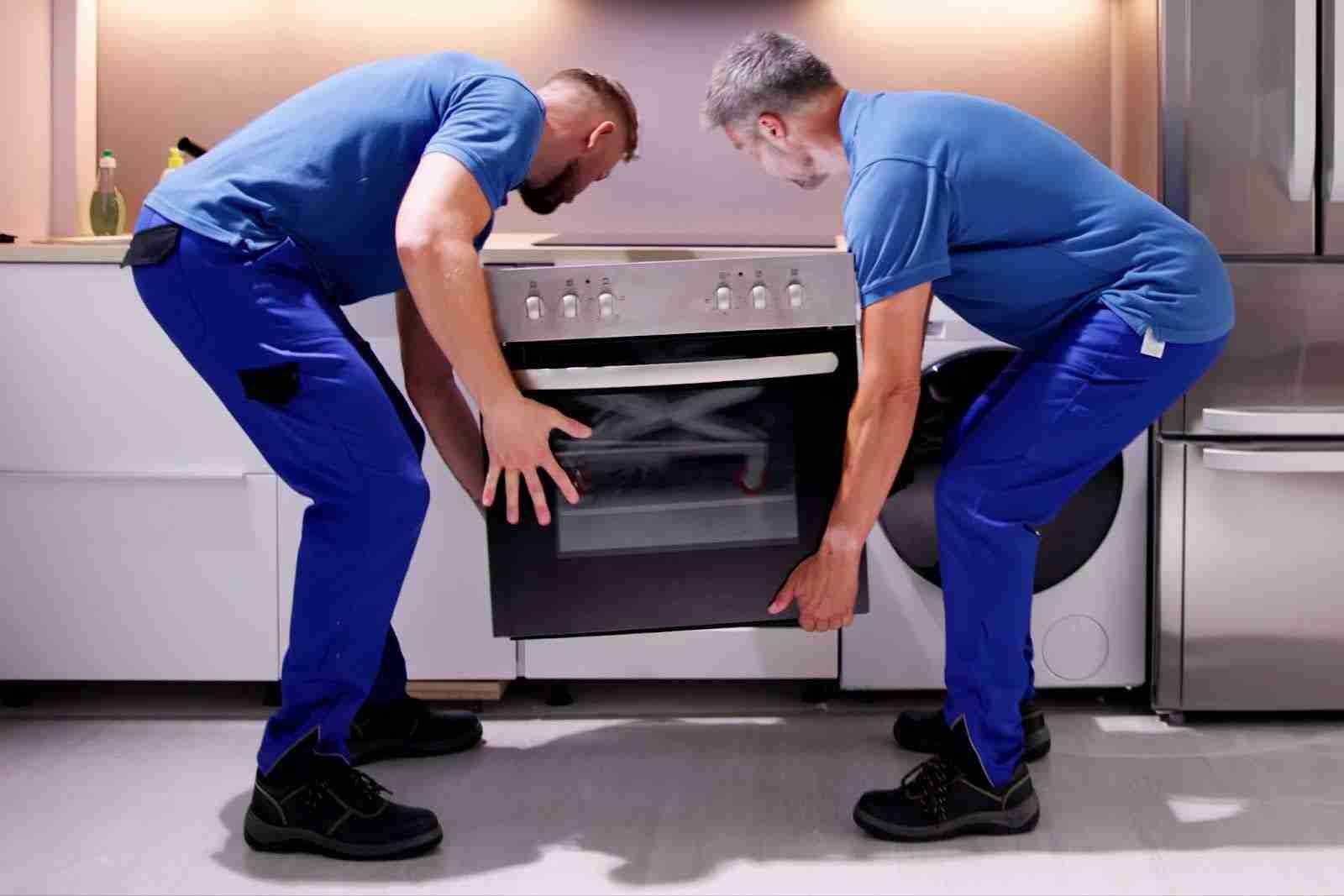 Two NW Akron movers carefully removing oven from kitchen
